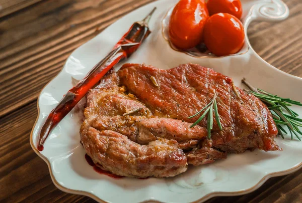 domates ve biberiye ahşap arka plan ile çanak üzerinde ızgara et