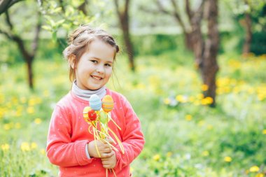 sarışın saçlı sevimli kız Paskalya yumurta tutar. Paskalya yumurta çayır üzerinde kızla