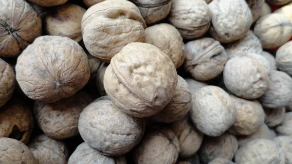 Heap of walnuts with peel. A large number of untreated walnut. — Stock Photo, Image