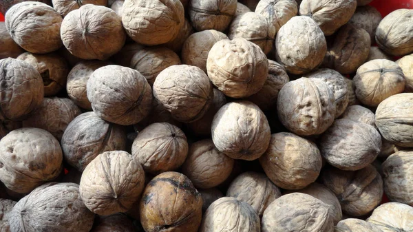 Heap of walnuts with peel. A large number of untreated walnut. — Stock Photo, Image