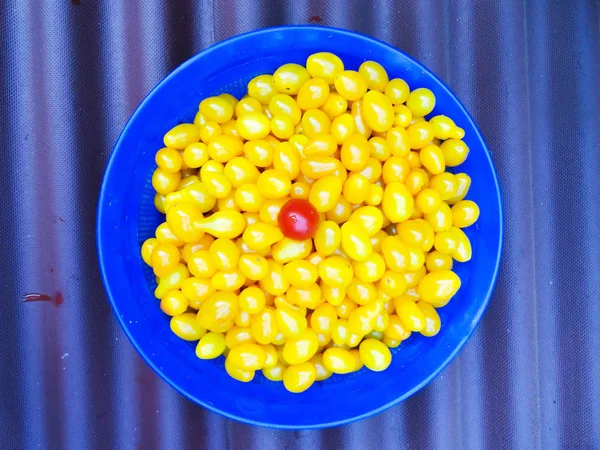 Pequeños tomates rojos y amarillos en los platos. Tomates jóvenes en una taza . — Foto de Stock