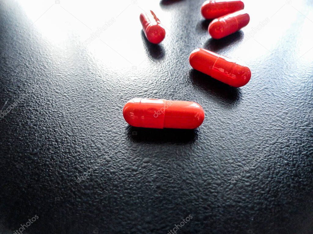 Photo of orange pills on a dark background.