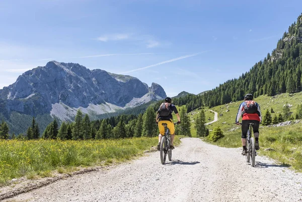 Dos ciclistas de montaña en los Alpes Cárnicos con vistas a la montaña Rosskofel —  Fotos de Stock