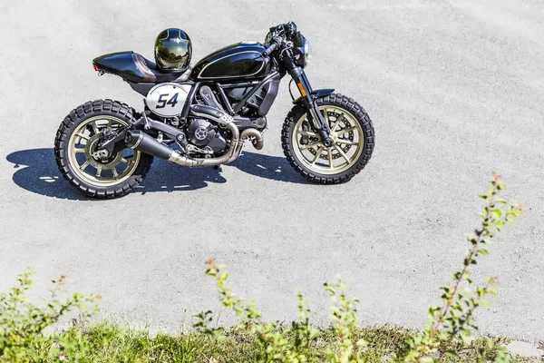 Maßgeschneiderte Scrambler-Stil Café Racer mit Helm steht auf r — Stockfoto