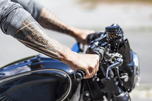 Tätowierungen auf den Armen von Motorradfahrern auf maßgeschneidertem Scrambler-Stall — Stockfoto