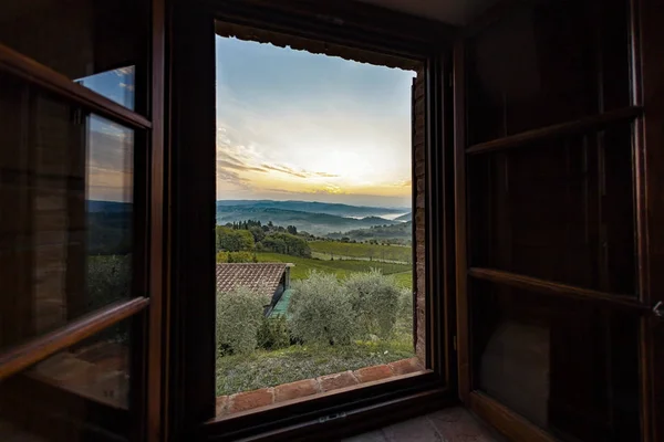 View through a window to a sunrise over foggy hills in Tuscany — Stock Photo, Image