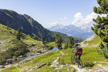 Mountainbiker downhill on Reiteralm with mountain Dachstein in S