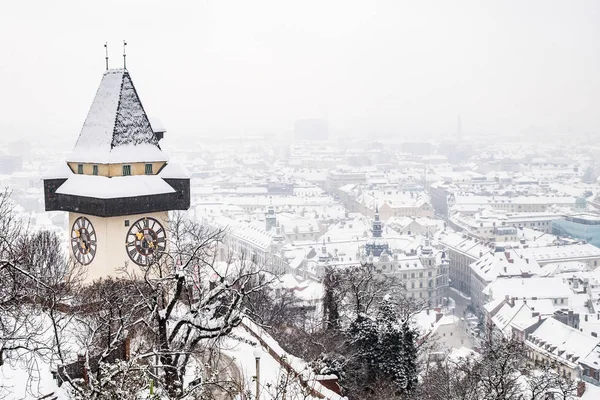 Snowy Uhrturm clocktower landmark on hill Schlossberg and city G — Stock Photo, Image