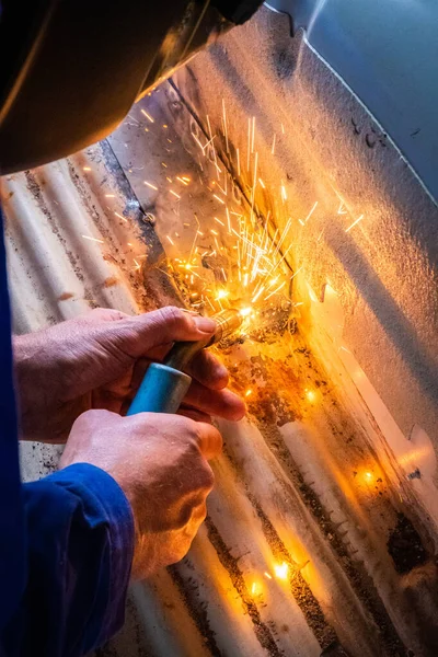 Man welds in metal of car and repairs rusty hole — Stock Photo, Image