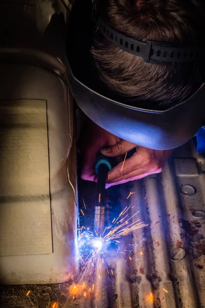 Man welds in metal of car and repairs rusty hole — Stock Photo, Image