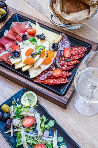 Antipasti on wooden plate, salad with anchovy, bread on paper — 스톡 사진