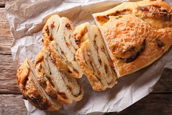 Delizioso pane con formaggio, pancetta e pomodori secchi primo piano. H — Foto Stock