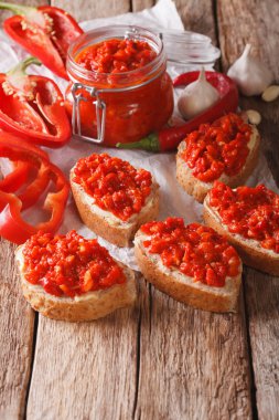 Ajvar bir cam kavanoz ve tost ahşap arka plan üzerinde. Dikey