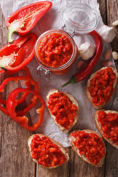 Ajvar dans un bocal en verre et pain grillé sur un fond en bois. Vertical — Photo