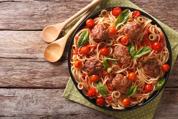 Spicy pasta with meatballs, olives, basil and tomato sauce close