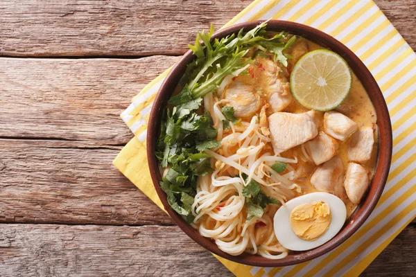 Malaysian laksa soup with chicken, egg, noodles and herbs close — Stock Photo, Image
