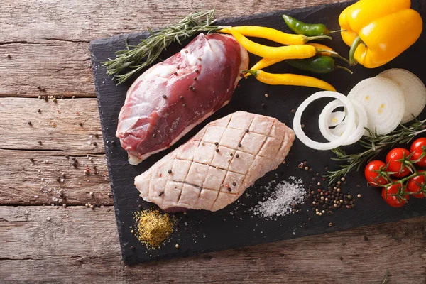 Poitrine de canard crue, avec légumes et épices en gros plan sur une planche . — Photo