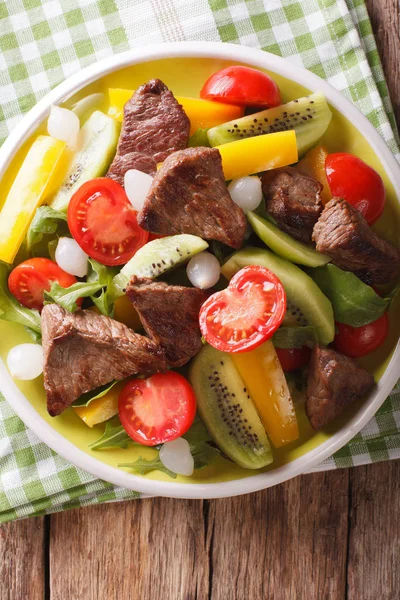 Salaatti naudanlihalla, kiivihedelmillä, tomaateilla, paprikoilla ja arugula lähellä — kuvapankkivalokuva