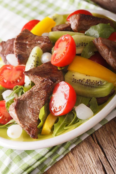 Juhlaruoka: Salaatti naudanlihalla, kiivillä, tomaateilla, pippurilla ja yrteillä — kuvapankkivalokuva
