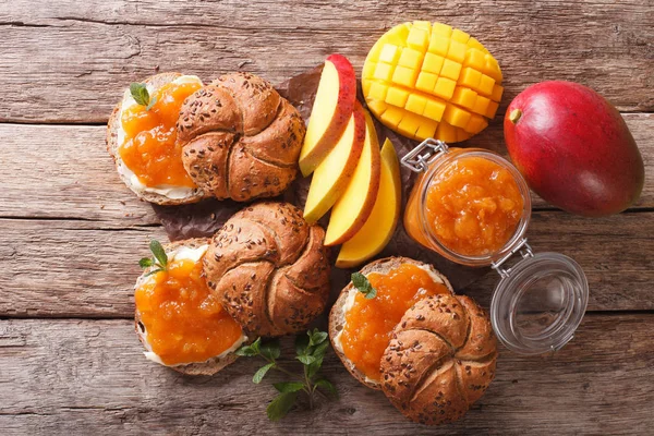 Сладкие свежеиспеченные роллы с джемом манго, маслом и мятой рядом - — стоковое фото