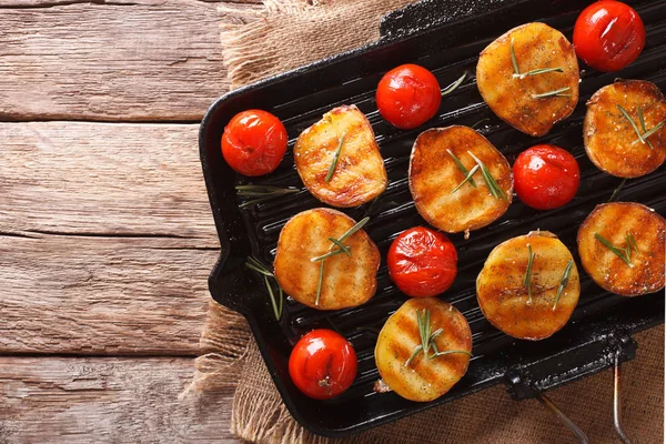 Sabrosas patatas asadas y tomates con romero de cerca en un —  Fotos de Stock