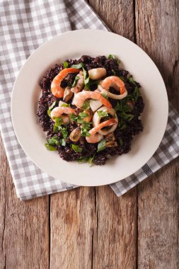 Paella deniz ürünleri yakın bir plaka üzerinde çekim ile siyah pirinç üzerinden. Vertica