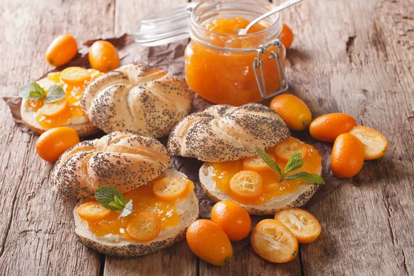 Kumquat jam in een glazen pot en zoete broodjes close-up. horizo — Stockfoto