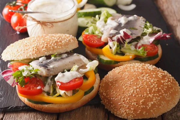 Fishburger met haring, jus en verse groenten close-up. Ho — Stockfoto