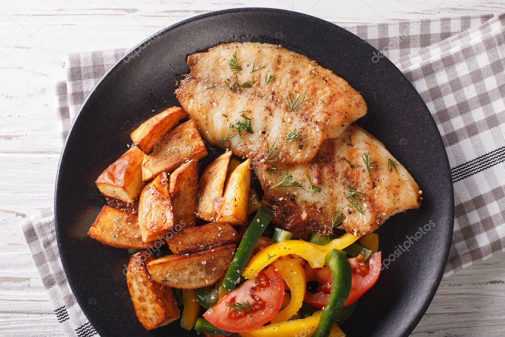 Grilled tilapia fillet, fried potatoes and a vegetable salad clo