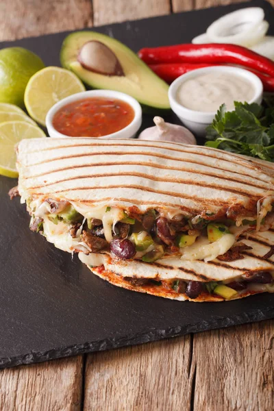 quesadilla with beef, beans, avocado and cheese close-up. vertic