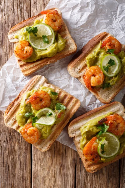 Tasty toast with guacamole, prawns and lime close-up. vertical t — Stock Photo, Image