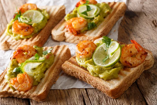 Delicious sandwiches with guacamole, shrimps and lime close-up.