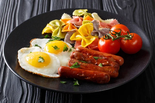 Farfalle pasta with fried eggs and sausages close-up. horizontal — Stock Photo, Image