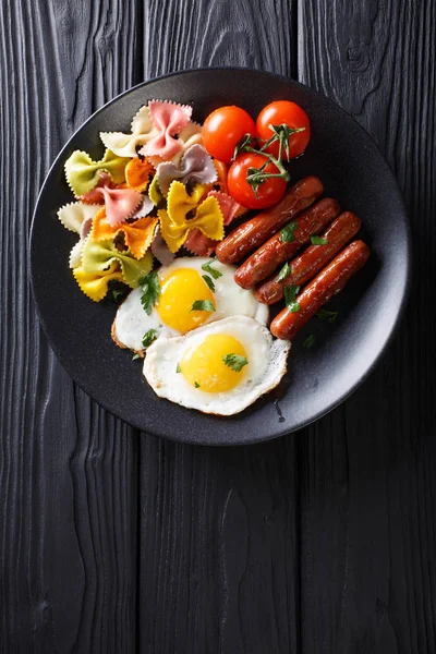 Hearty breakfast: fried eggs, sausages, farfalle pasta and tomat — Stock Photo, Image