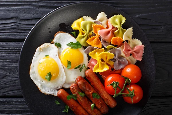 Τηγανητό αυγό, λουκάνικα, ζυμαρικά φιογκάκια και ντομάτα γκρο πλαν. Ορίζοντα — Φωτογραφία Αρχείου