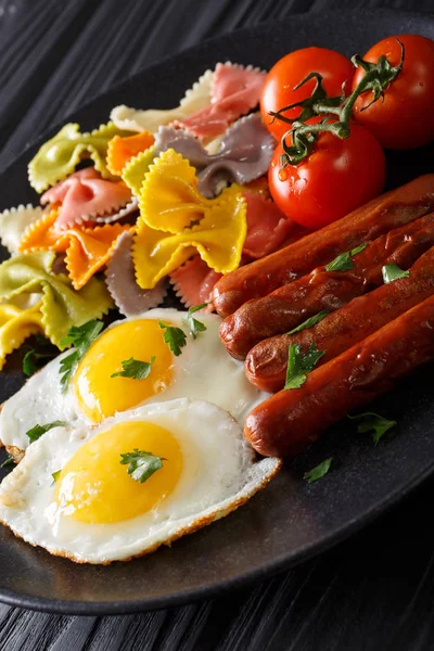 Hearty breakfast: fried eggs, sausages, farfalle pasta and tomat — Stock Photo, Image