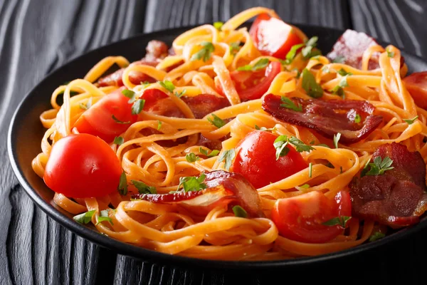 Carrot pasta with fried bacon, greens and tomatoes close-up on t — Stock Photo, Image