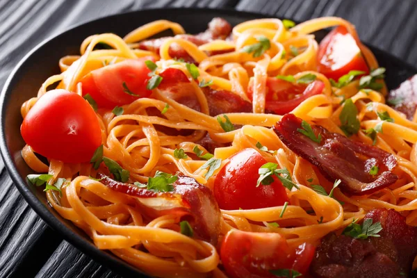 Karottennudeln mit gebratenem Speck und Tomaten in Großaufnahme auf einem Teller. h — Stockfoto