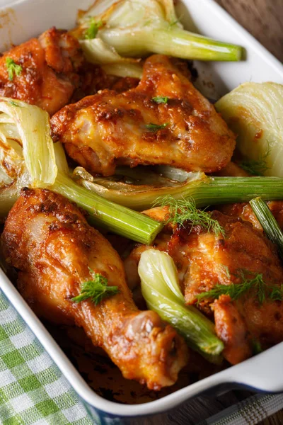 spicy chicken baked with fennel in a baking dish close-up. verti