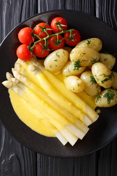 Espargos saborosos com molho holandês e batatas close-up em — Fotografia de Stock