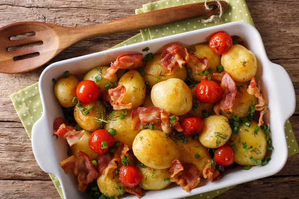 Patate novelle al forno con pancetta, erbe aromatiche e pomodori primo piano in un — Foto Stock