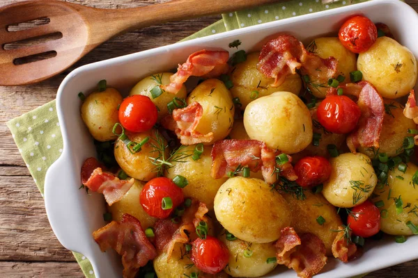 Pommes de terre nouvelles savoureuses cuites au four avec du bacon, des herbes et des tomates macro dans — Photo
