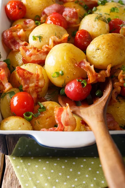 Hot new potatoes baked with bacon and tomatoes close-up. vertica — Stock Photo, Image