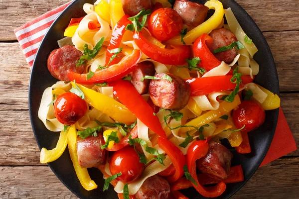 Noodles with stewed bell pepper and sausages close-up on a plate — Stock Photo, Image