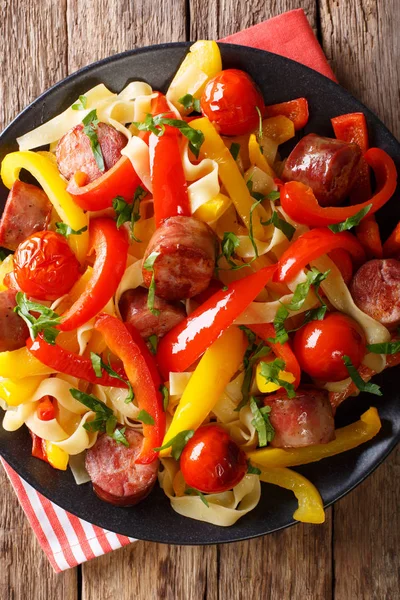 Noodles with stewed bell pepper and sausages close-up on a plate — Stock Photo, Image