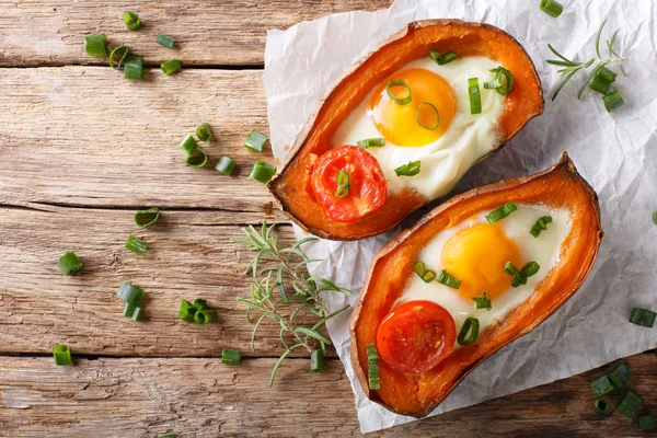 Baked sweet potato stuffed with egg and tomato close-up on the t — Stock Photo, Image