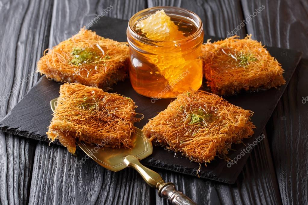 Sweet oriental dessert kunafeh with pistachios and fresh honey c