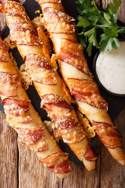 Bread sticks baked with bacon and cheese close-up on the table. vertical view from abov