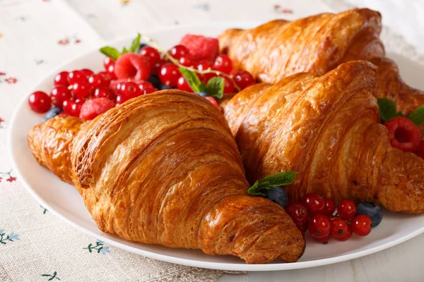 Smör croissant med färska bär som närbild på en tallrik. Horisont — Stockfoto