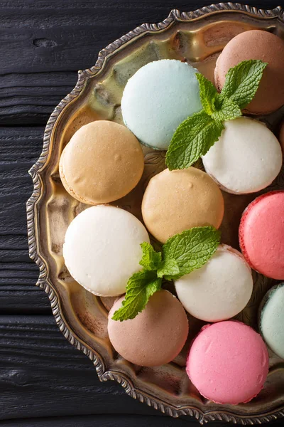 Multicolored macaroons and fresh mint closeup on a platter. Vert — Stock Photo, Image